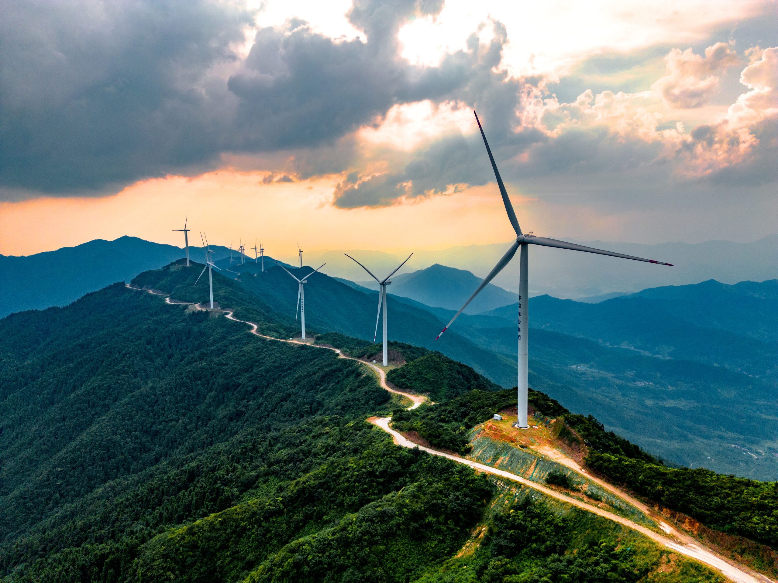 Wind farm with turbines along a remote mountain ridge, linked by an access road
