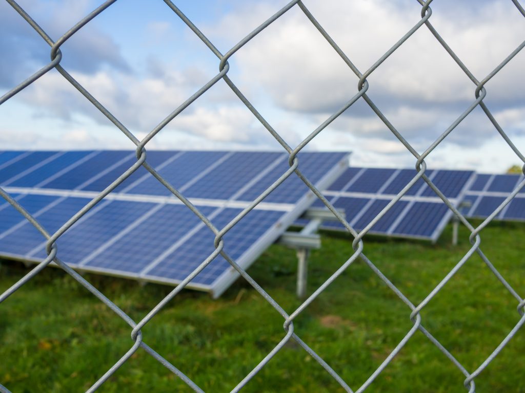 Solar farm panels seen through a chain-link perimeter fence